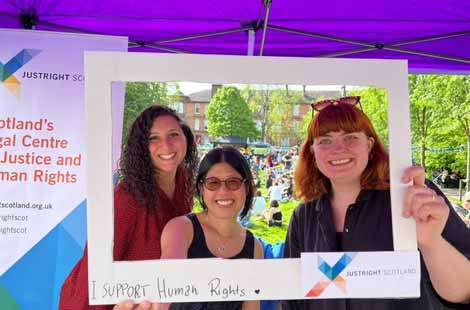 Three women holding up a frame with the words I support human rights, and the Just Right Scotland logo.